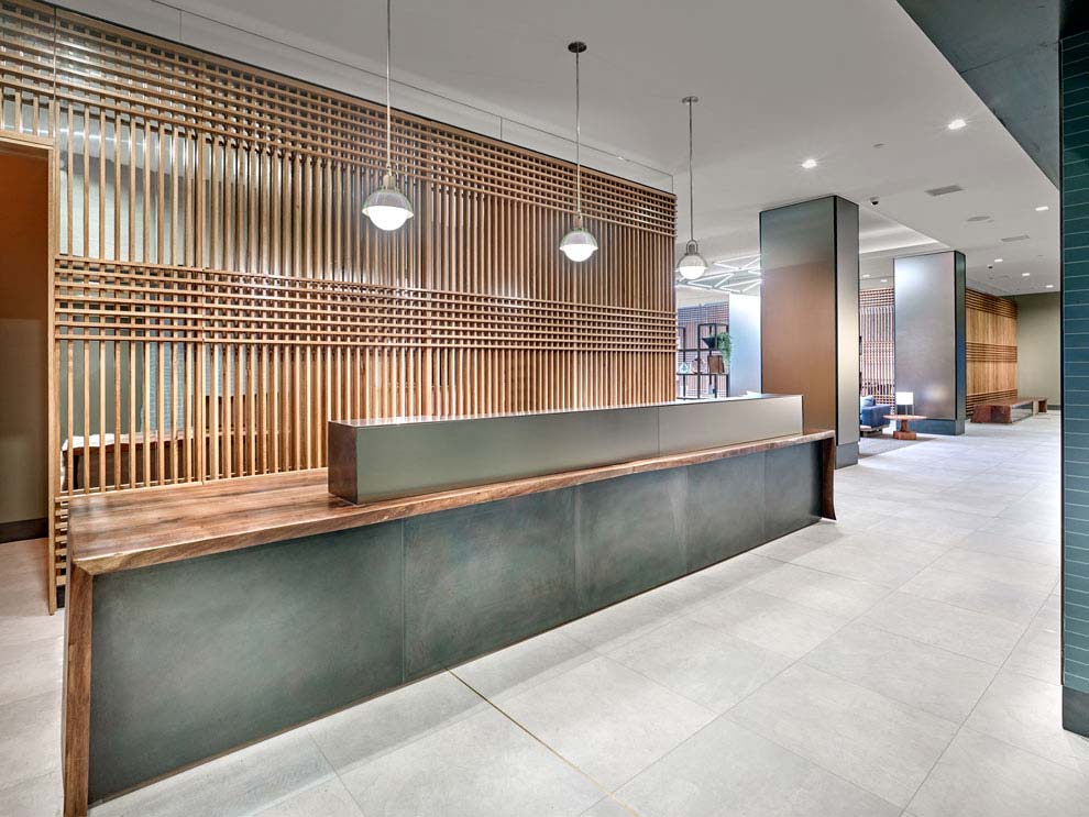 Main Lobby reception desk with pendant lighting in front of hardwood feature wall. 