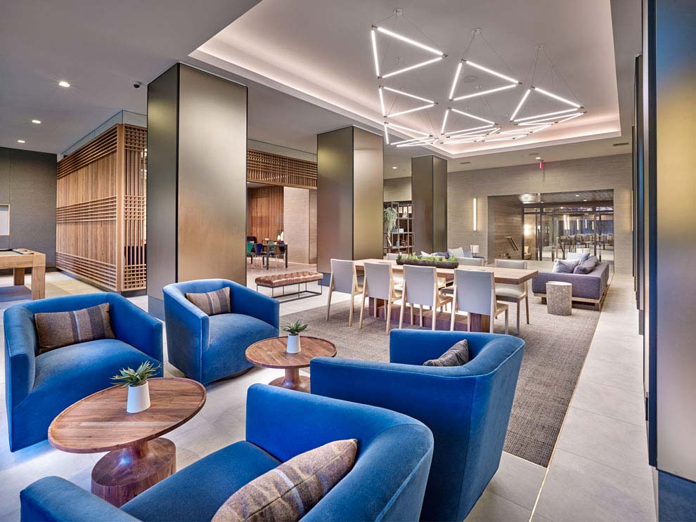 Interior of modern lobby with plush chairs, pool table, backlit tray ceiling and conference table.